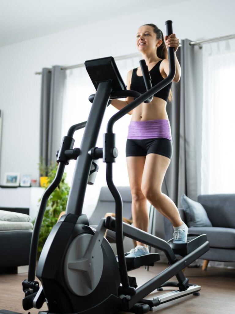 Frau trainiert zuhause auf dem Crosstrainer – Hybrid Coaching von AURUM Health & Performance in Therwil mit flexiblen Online- und Studio-Trainings.